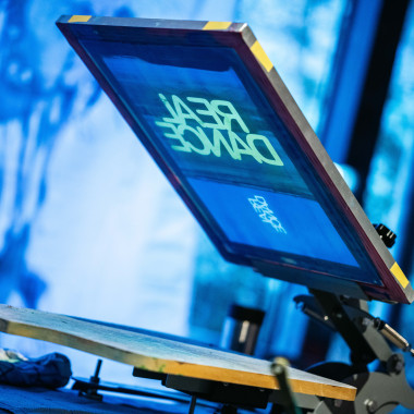 Eine Siebdruckmaschine im Festivalzentrum. Es zeigt das Motiv "REAL DANCE".